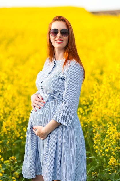 Pregnant woman portrait on the yellow field