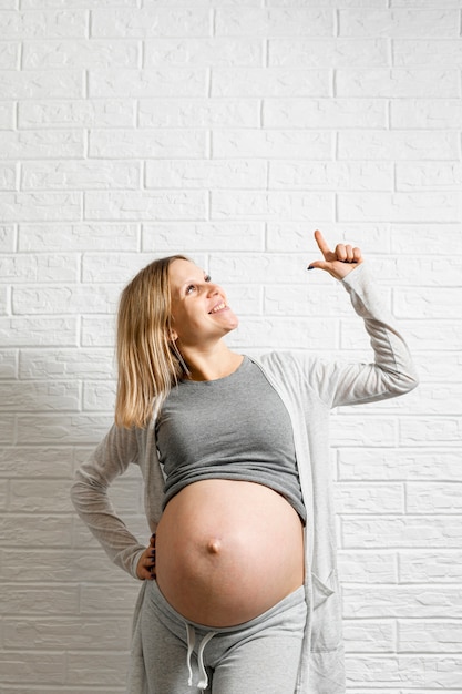 Photo pregnant woman posing in front of a white wall