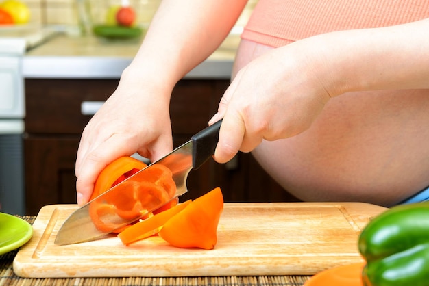 Photo pregnant woman preparing a pepper in the kitchen