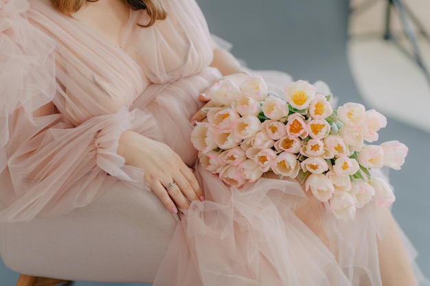 ふくらんでいるピンクのドレスを着た妊婦の優雅さと妊娠