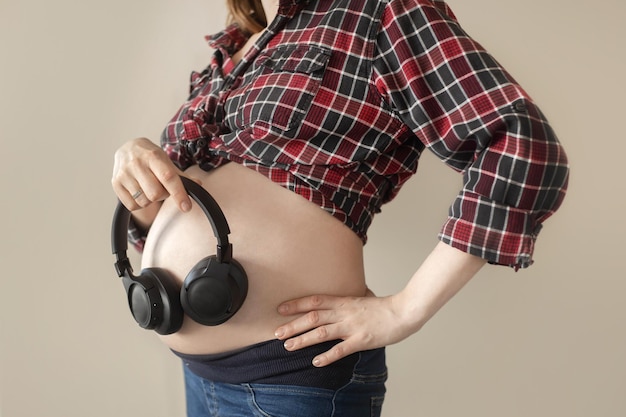A pregnant woman puts headphones to her stomach