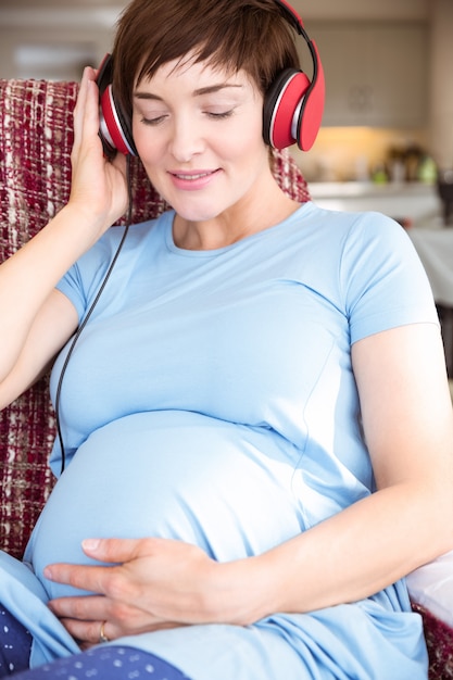 Pregnant woman putting headphones over bump