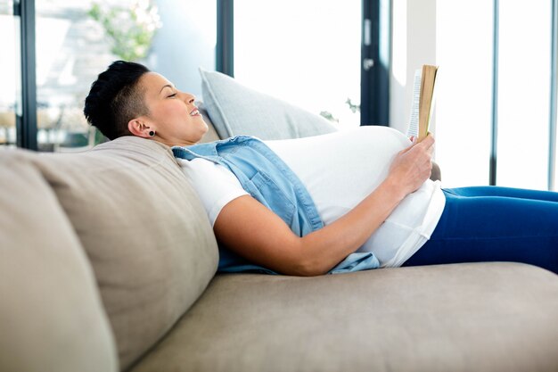사진 거실에서 소파에 누워있는 동안 책을 읽고 임신 한 여자