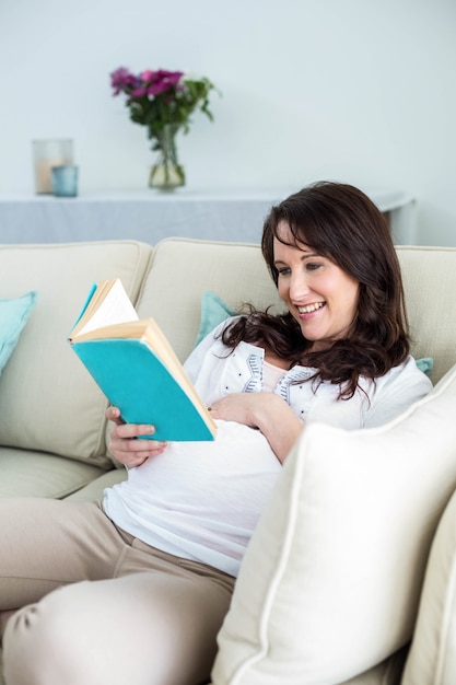 Pregnant woman reading a book in living room