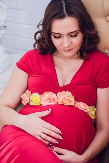 Pregnant woman in a red dress lying on the sofa