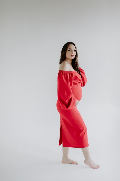 Pregnant woman in red dress on white