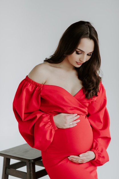 Pregnant woman in red dress on white