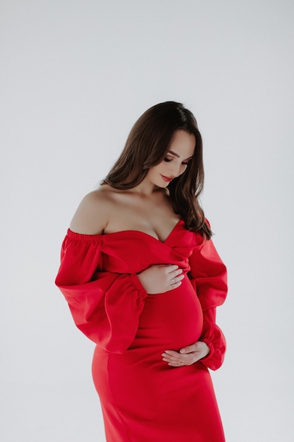 Pregnant woman in red dress on white