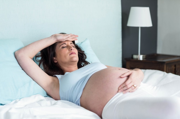 Беременная женщина отдыхает на своей кровати у себя дома