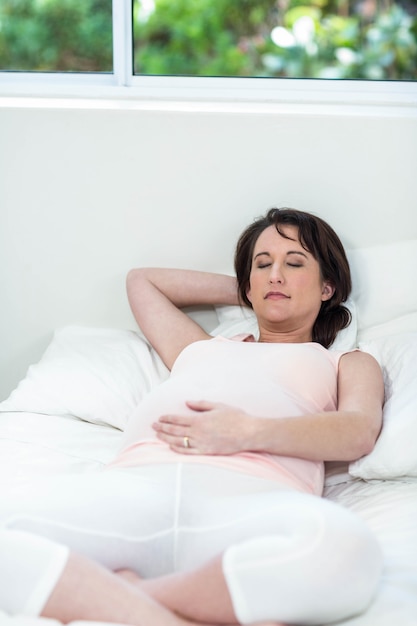 Pregnant woman resting on her bed at home 