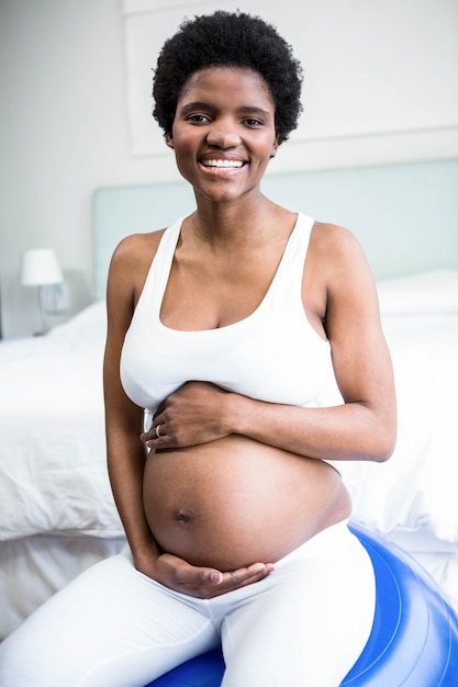 Pregnant woman rubbing her belly sitting on exercise ball