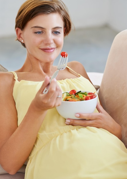 Pregnant woman salad and smile on sofa for health nutrition and wellness in living room of apartment Person vegetables or happy on couch of lounge for relax pregnancy and healthy diet with fiber