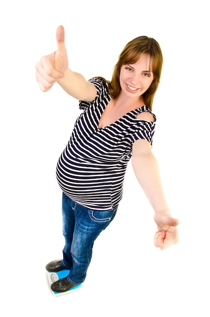 Pregnant woman on a scales giving a thumb up