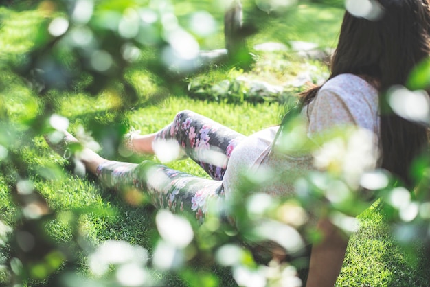 写真 公園に座っている植物を通して見られる妊婦