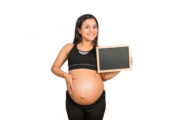 Pregnant woman showing something on chalkboard.