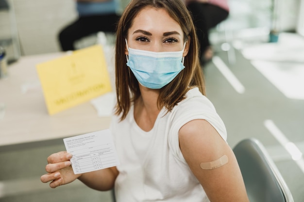 A pregnant woman showing vaccination certificate after receiving the Covid-19 vaccine. Looking at camera.