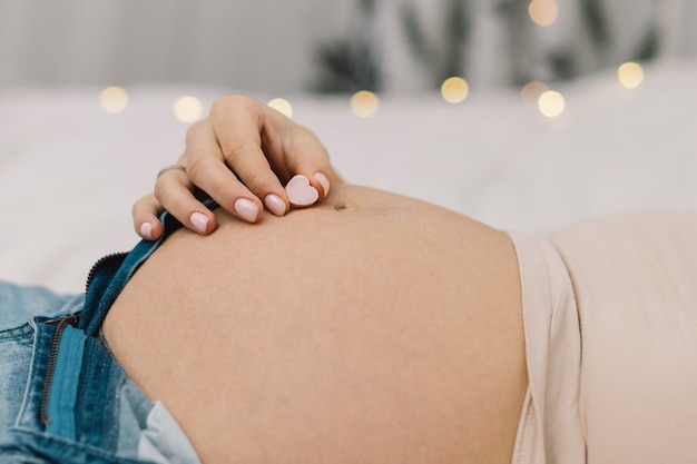 Pregnant woman shows heart on her big belly.