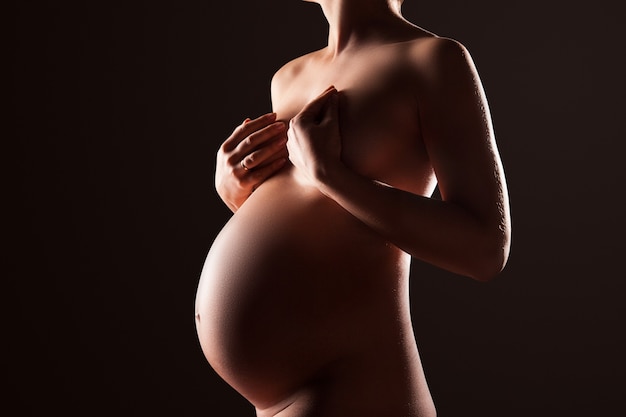 Pregnant woman silhouette over black background. Side view