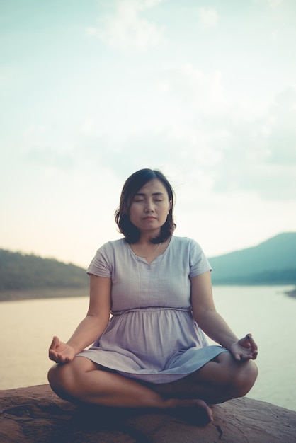 Pregnant woman sit on the rock for play yoga side damvintage stylepastel tonedarkfilm