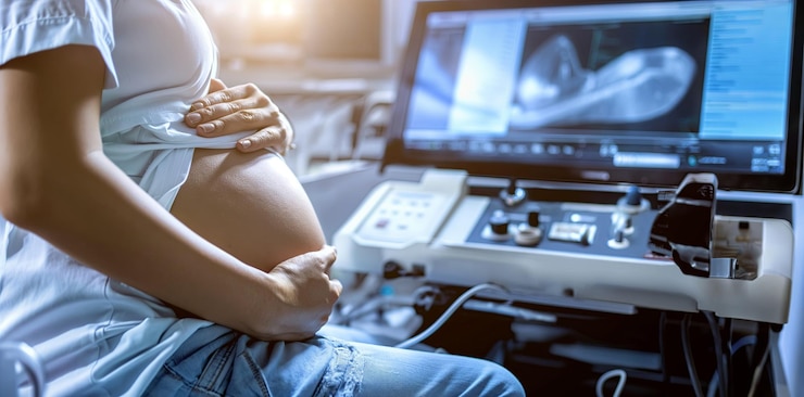 Photo a pregnant woman sits in front of a monitor with the words baby on it