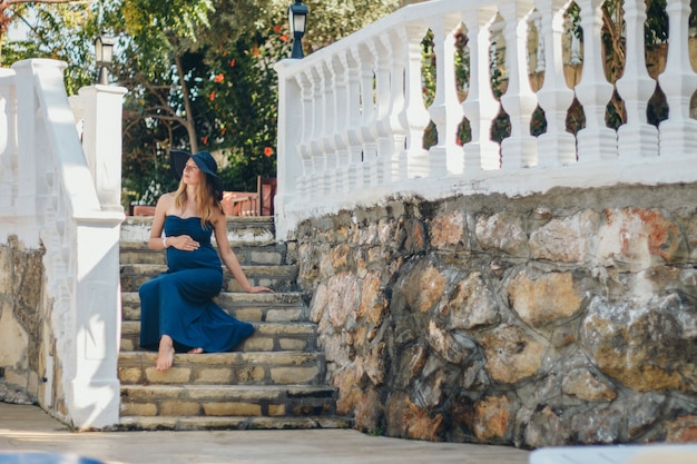 A pregnant woman sits on the stone steps of a historic building. Tourist on an excursion. Girl on vacation