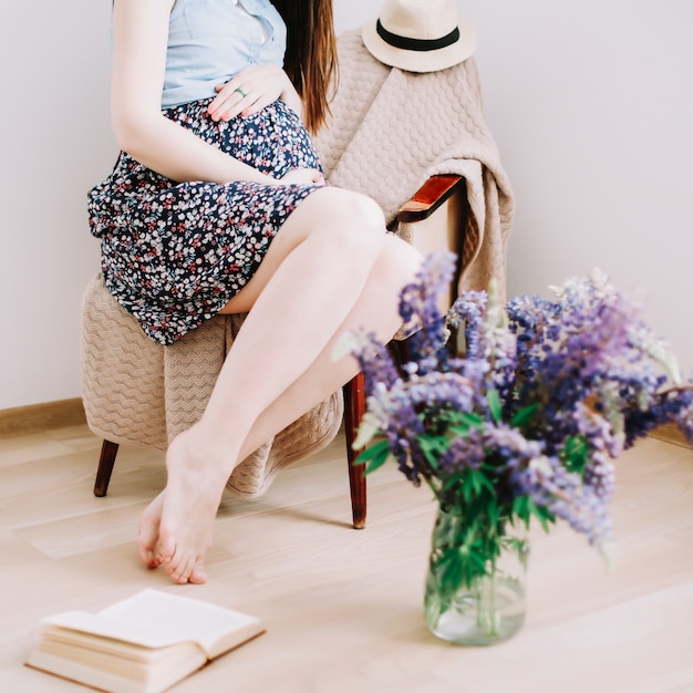 Pregnant woman sitting in the armchair at home pregnancy maternity preparation and expectation concept