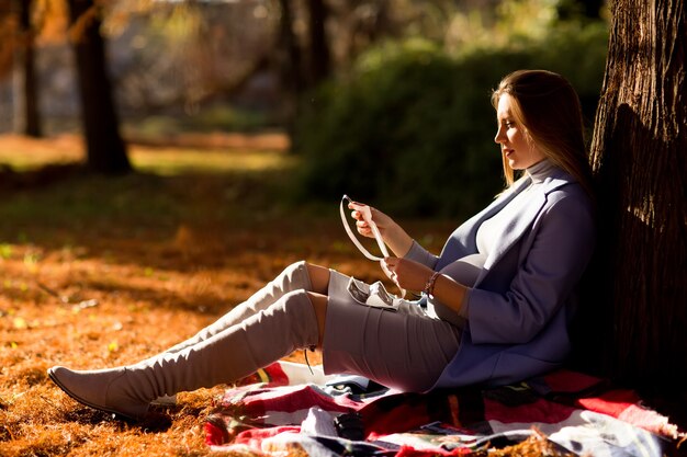 Pregnant woman sitting under autumn tree