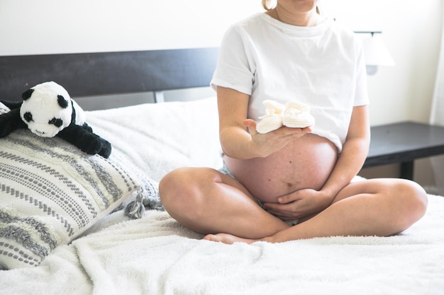 Pregnant woman sitting on a bed holding The concept of pregnancy motherhood and prenatal care Mom with a new life