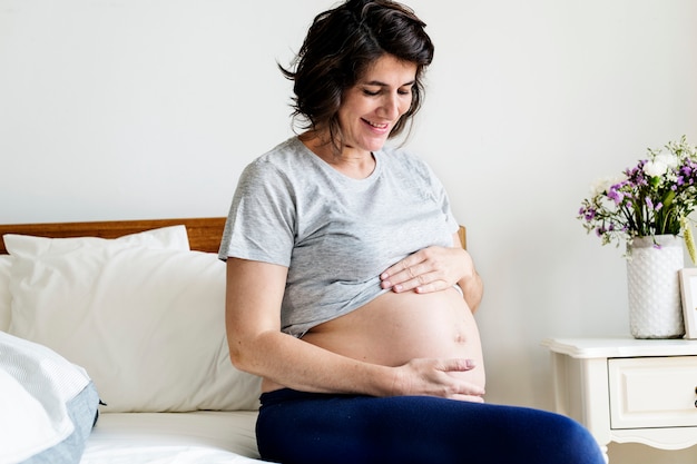 妊娠中の女性がベッドの上に座って