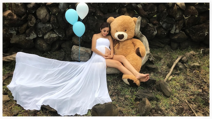 Photo pregnant woman sitting by balloons and stuffed toy on rock