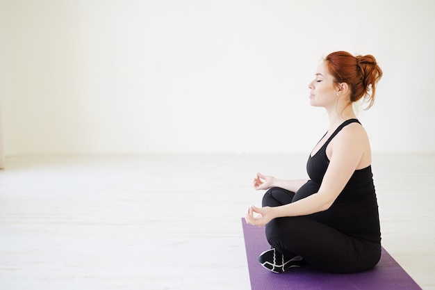 Foto donna incinta che si siede nel meditare di posa del loto