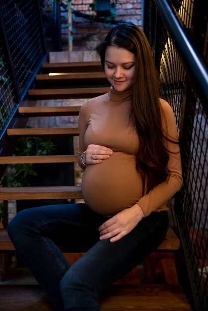 Pregnant woman sitting on staircase inside building