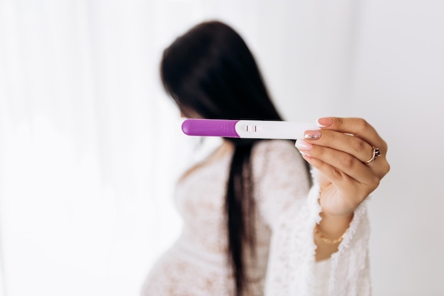 Photo pregnant woman sitting strokes hugging the belly tummy abdomen hold pregnancy test kit