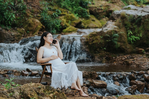 Pregnant woman sitting at the waterfall