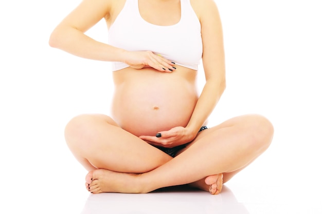 흰색 배경 위에 앉아 임신 한 여자
