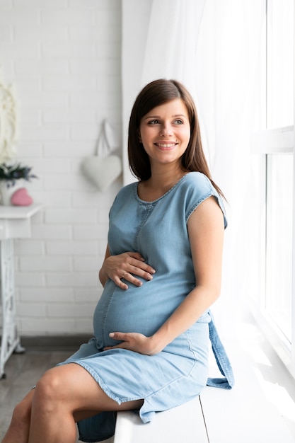Photo pregnant woman sitting next to window