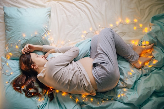 Pregnant woman sleeping on bed