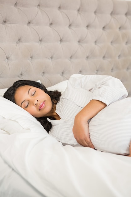 Foto donna incinta che dorme nella camera da letto