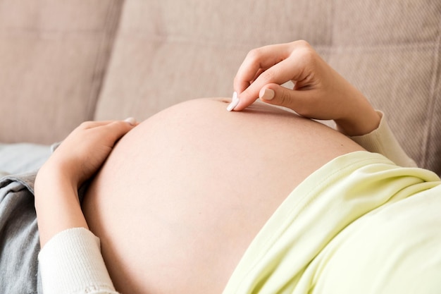 Photo pregnant woman on sofa and touching her belly at home pregnancy expectation concept