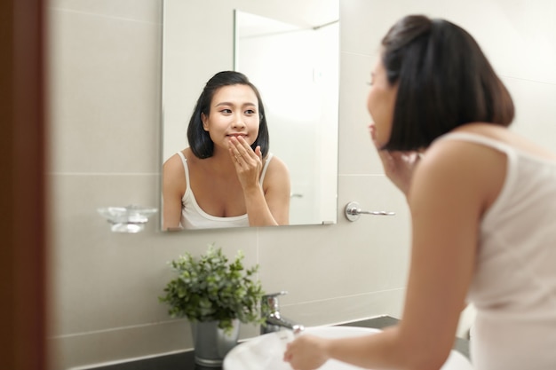 Pregnant woman splashing face with water above bathroom sink