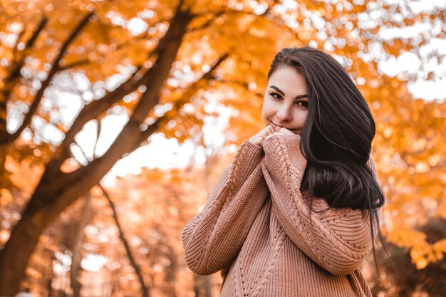 Pregnant woman standing in autumn city park forest, dressed warm woolen sweater, round belly