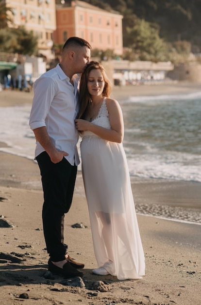 Pregnant woman standing on the beach with her husband