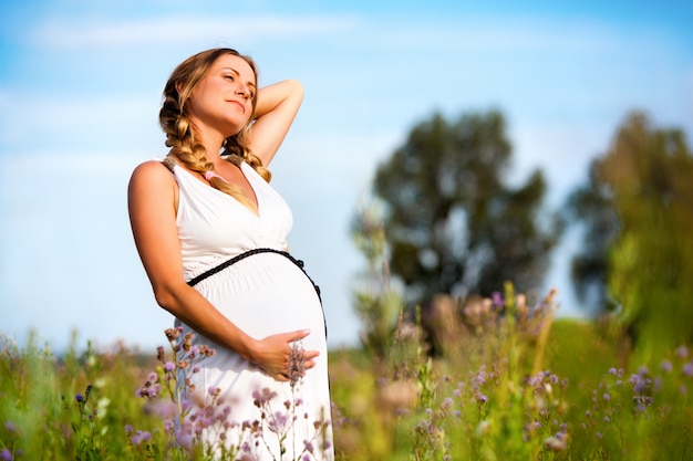 Photo pregnant woman standing in flower field