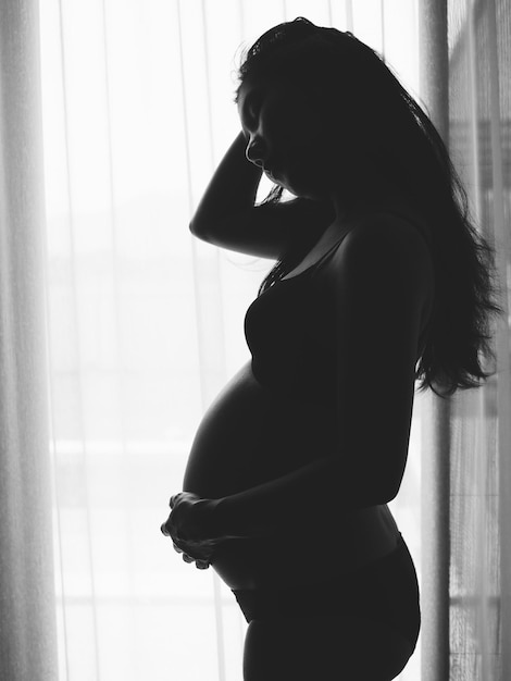 임신 한 여자 가 집 에 서 있다