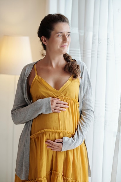 Беременная женщина стоит дома