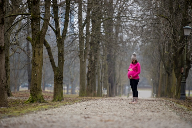 Pregnant woman standing outside in a park