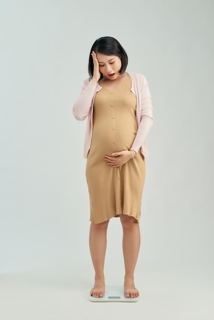 Pregnant woman standing on scales at home Pregnancy weight gain concept