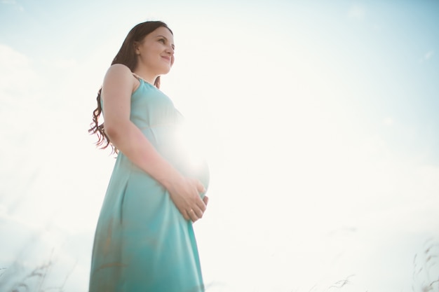 Pregnant woman standing touching her belly