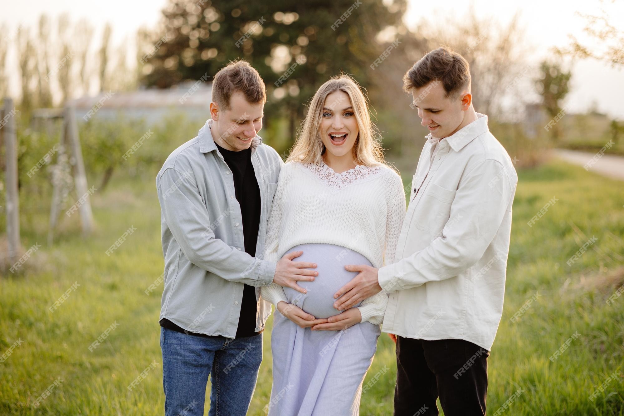 Premium Photo | A pregnant woman stands in a field with her husband and the  pregnant woman is holding her belly.