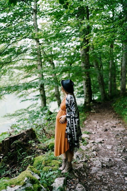 Pregnant woman stands on a path in the park